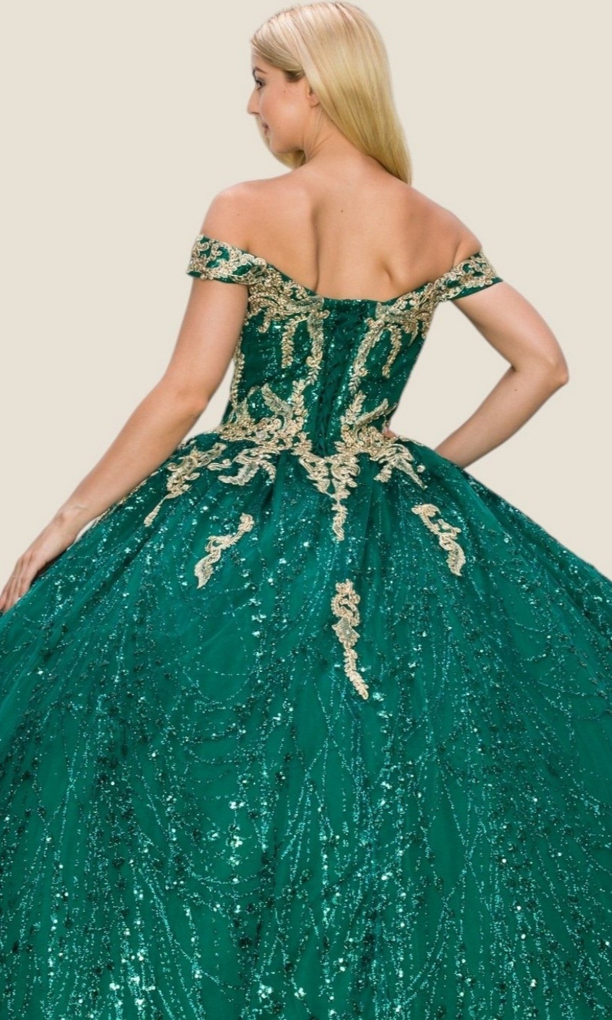 A woman showcases the Quinceanera Dress 4201 by Cinderella Couture, an off-shoulder emerald green ball gown adorned with gold embroidery and sequins, as she poses from the back against a simple light background, radiating timeless elegance.